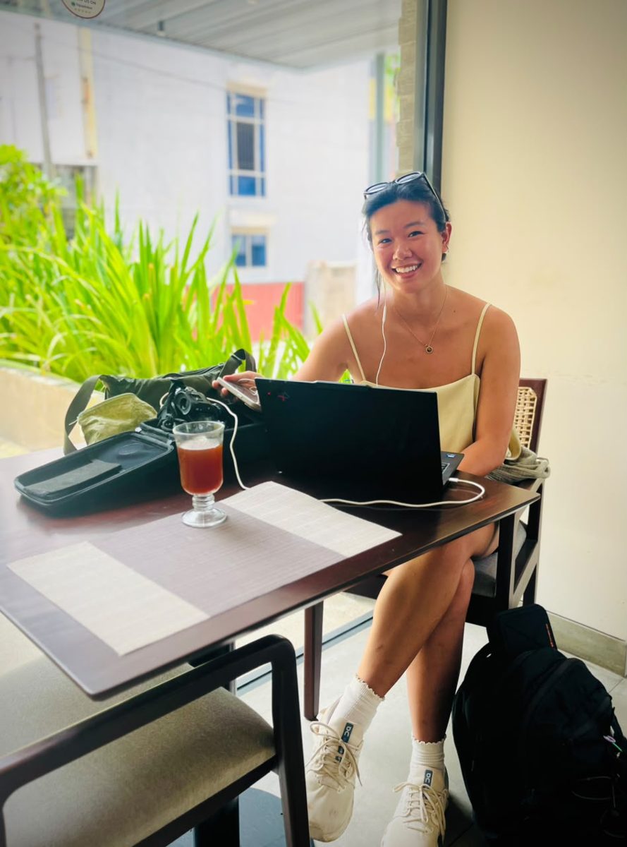 A smiling guest working on a laptop at a terrace table at Taprobane House