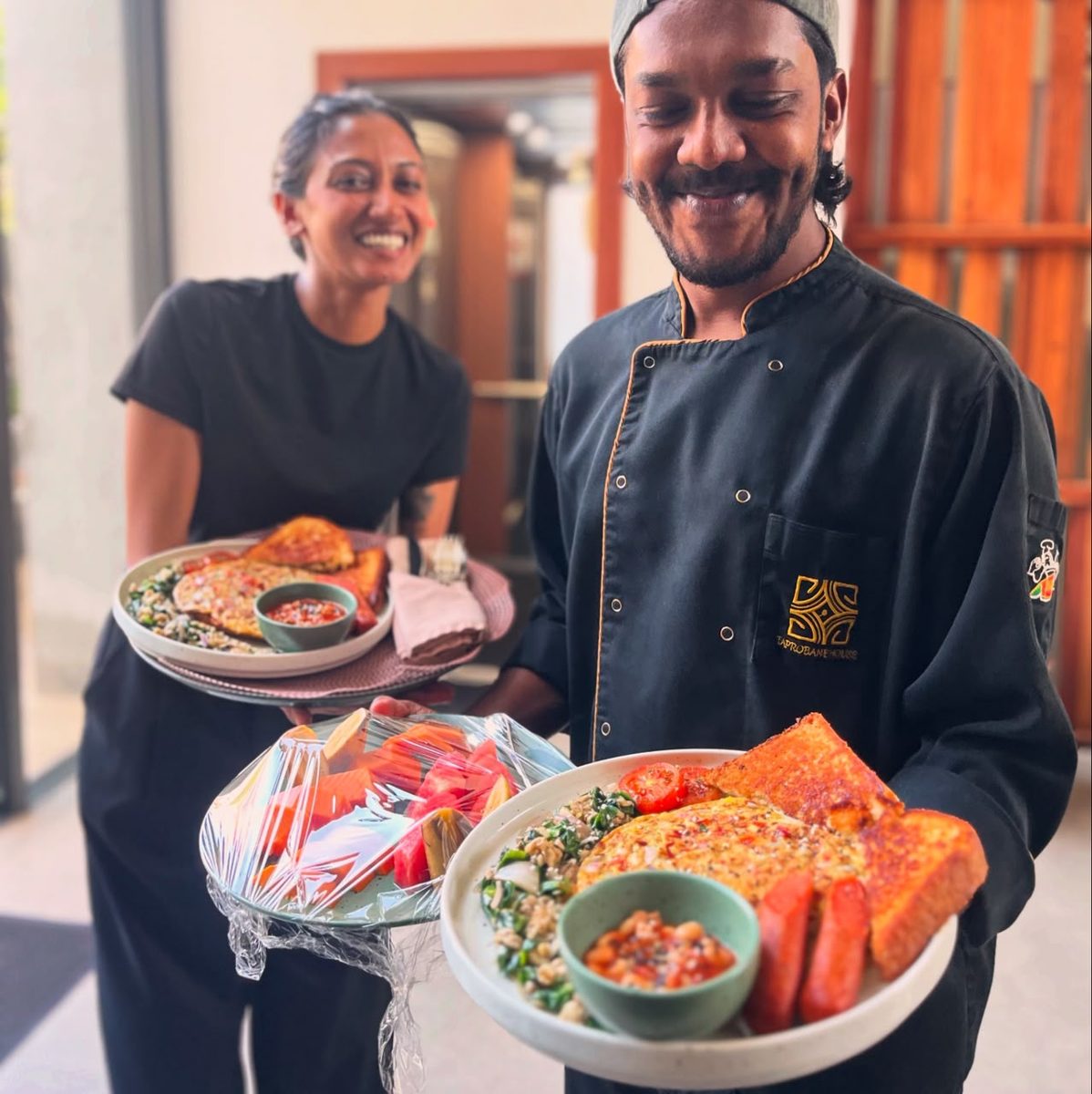 Taprobane House chef and server smiling as they bring out a full Sri Lankan breakfast